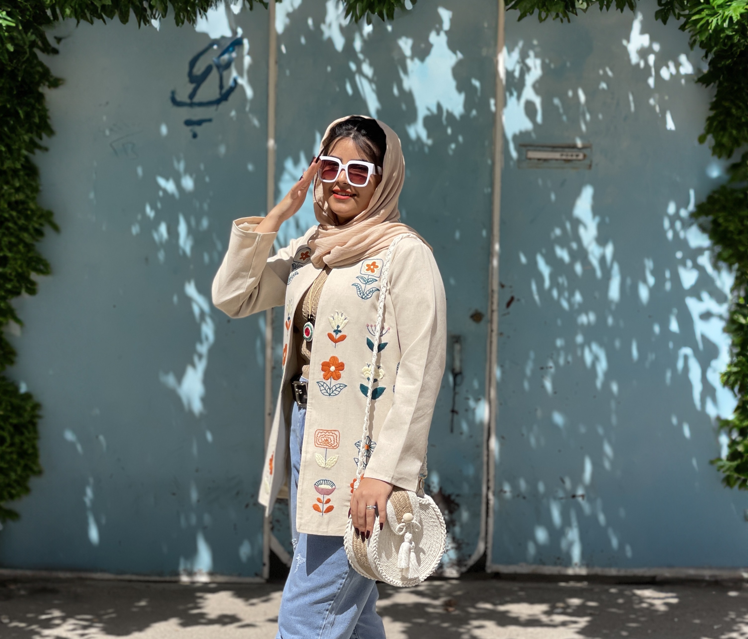 A young girl wearing a hand-embroidered blazer by DooziStyle in front of a blue door
